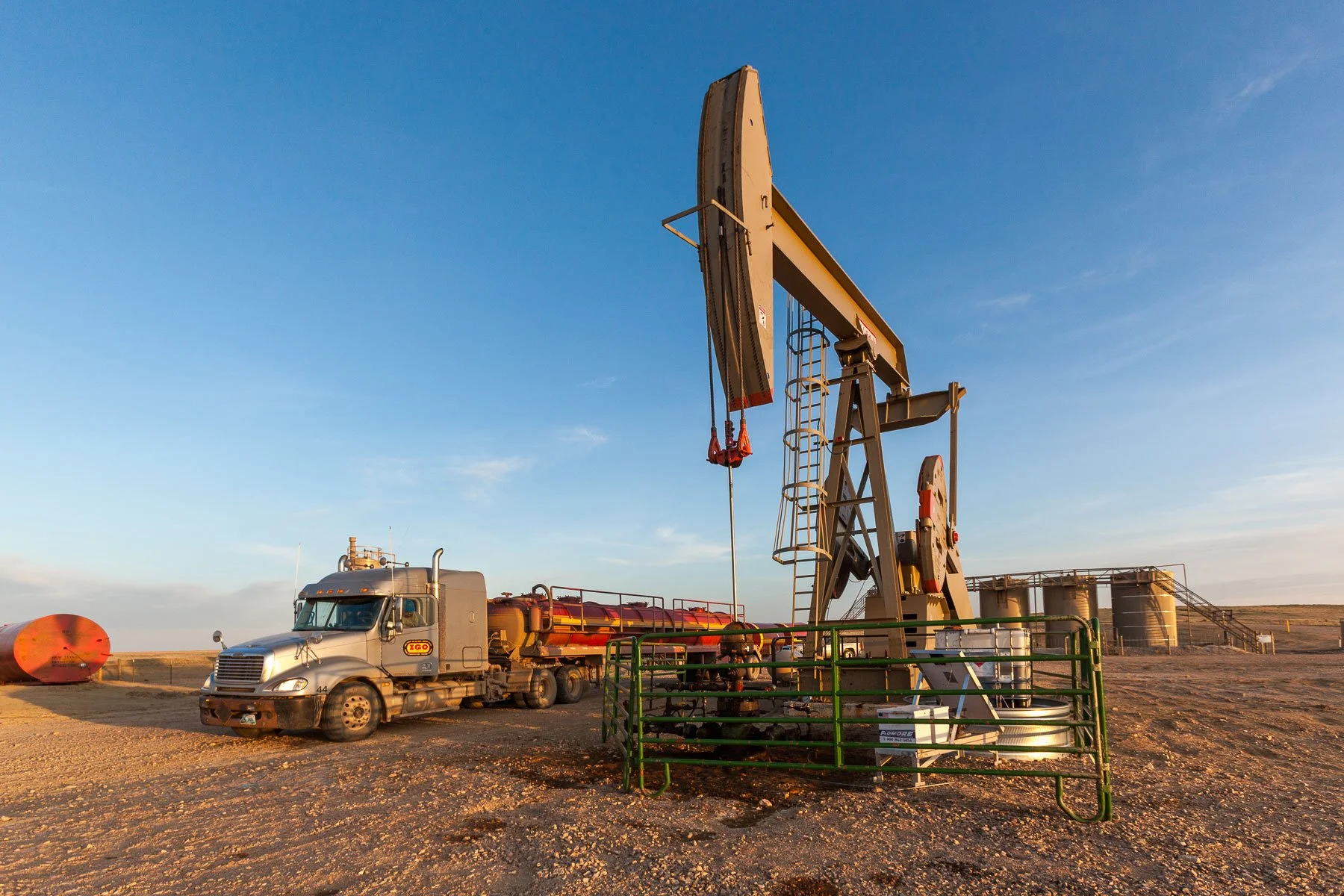 Oil pump jack and tanker truck in an oil field during sunset near Douglas, Wyoming.