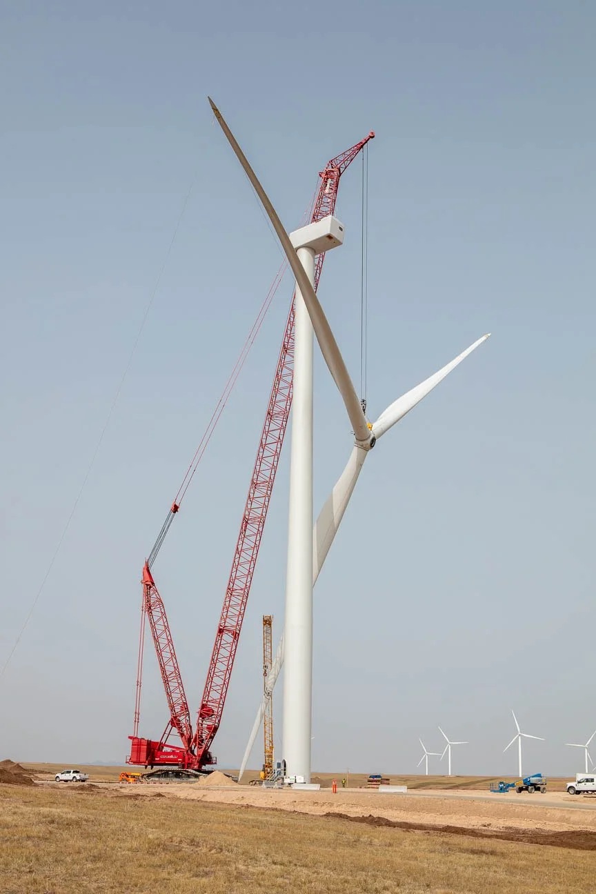 Wind turbine construction photography for Black Hills Corporation including a crane lifting and installing a turbine head and blades.