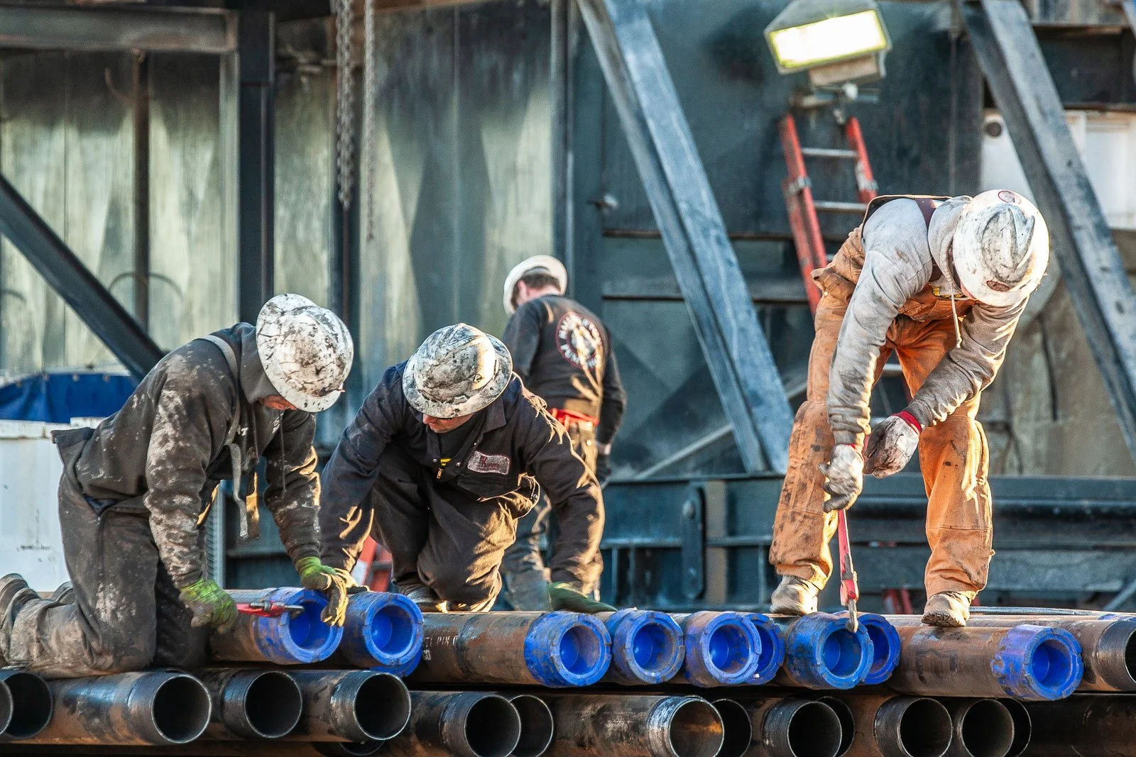 Oil field workers take the caps off of casing pipe near an oil and gas drilling rig in Wyoming.