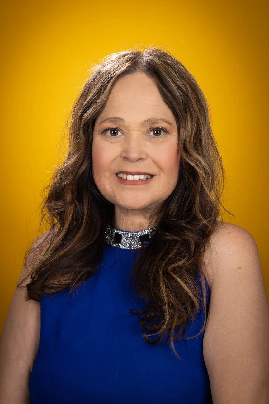 Business headshot portrait including a yellow background.