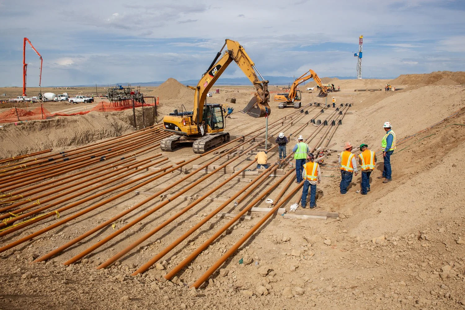 Gas pipeline construction with a gas drilling rig in the background.