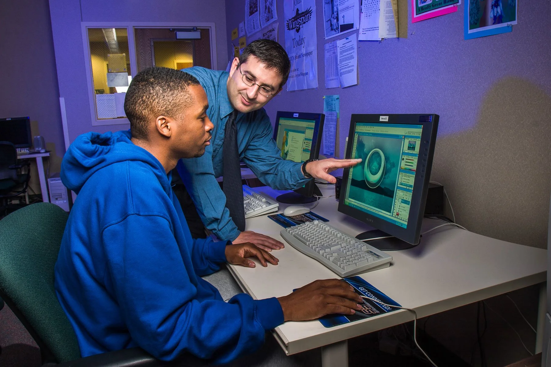 Education and training photography for marketing and editorial use, including a teacher with a student in a computer lab.