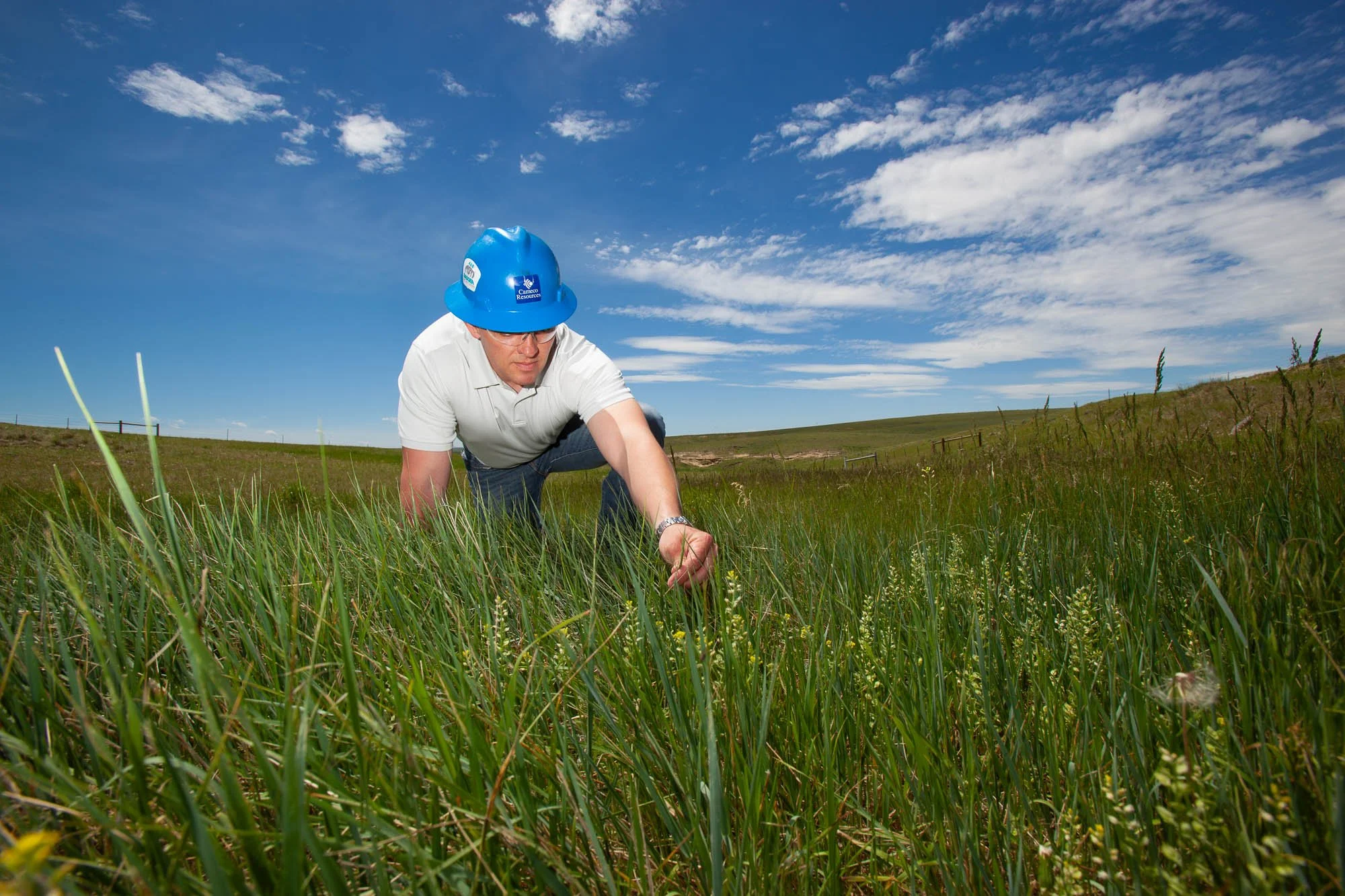 An industrial worker at a Uranium mine in Central Wyoming looks at grass at a reclaimed site.