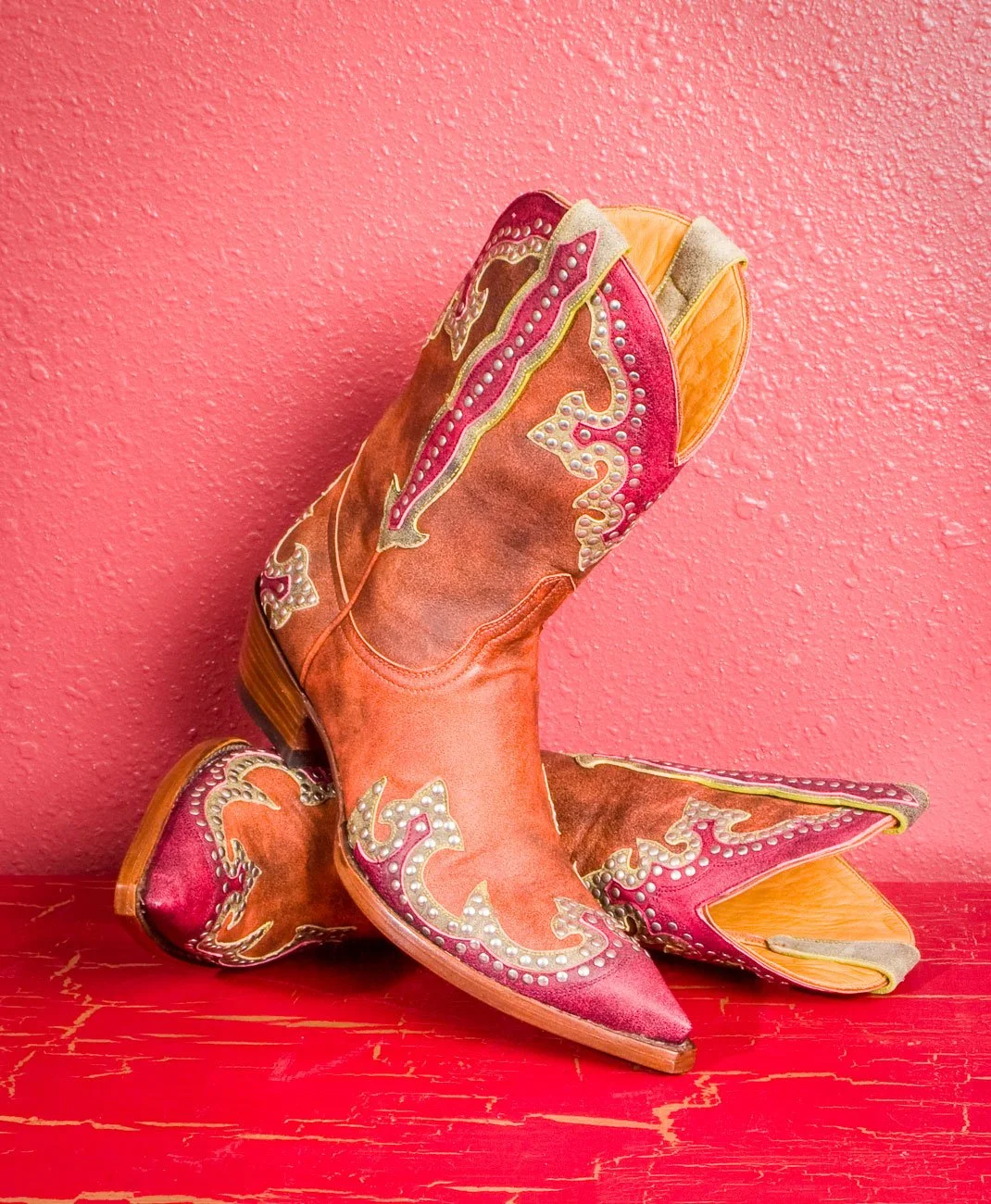 Pink cowboy boots on a pick background product photography.
