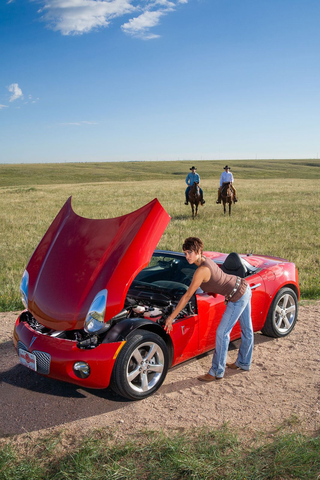 Portrait with product for marketing for a western store in Cheyenne, Wyoming. A woman with a broken-down car and 2 cowboys riding to rescue her.