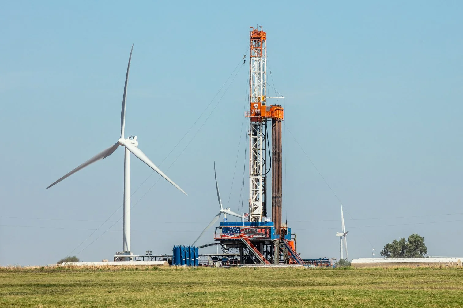 Patterson-UTI Drilling rig and wind turbines in background in Okarche, Oklahoma.