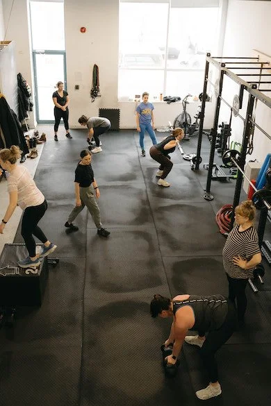 A group of women strength training in a Toronto Gym using weights.