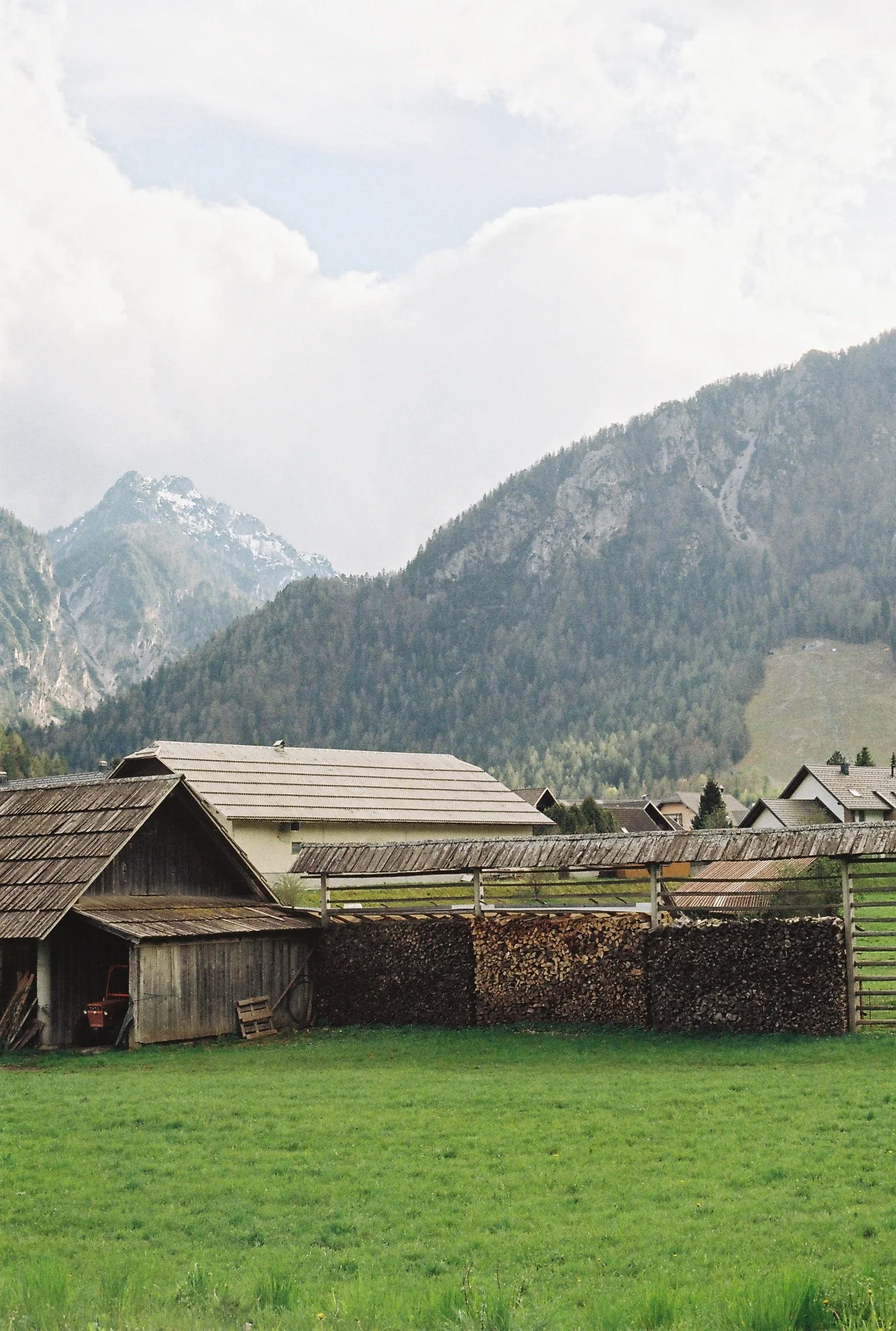 Maisons en bois avec une montagne en arrière-plan et une pelouse verte au premier plan.