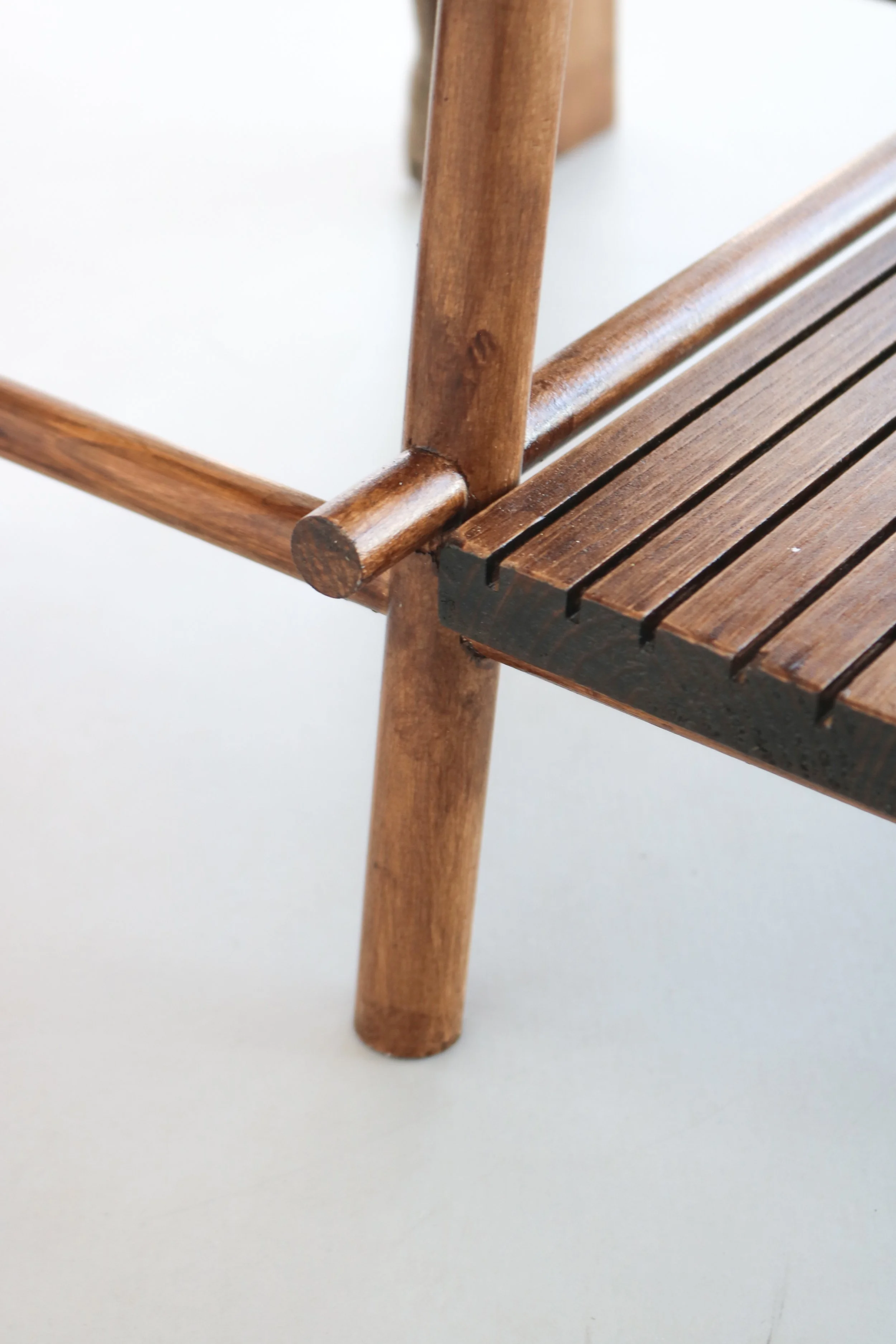 Pièce de mobilier en bois avec une structure en bois clair et une assise en bois foncé, légèrement abîmée.