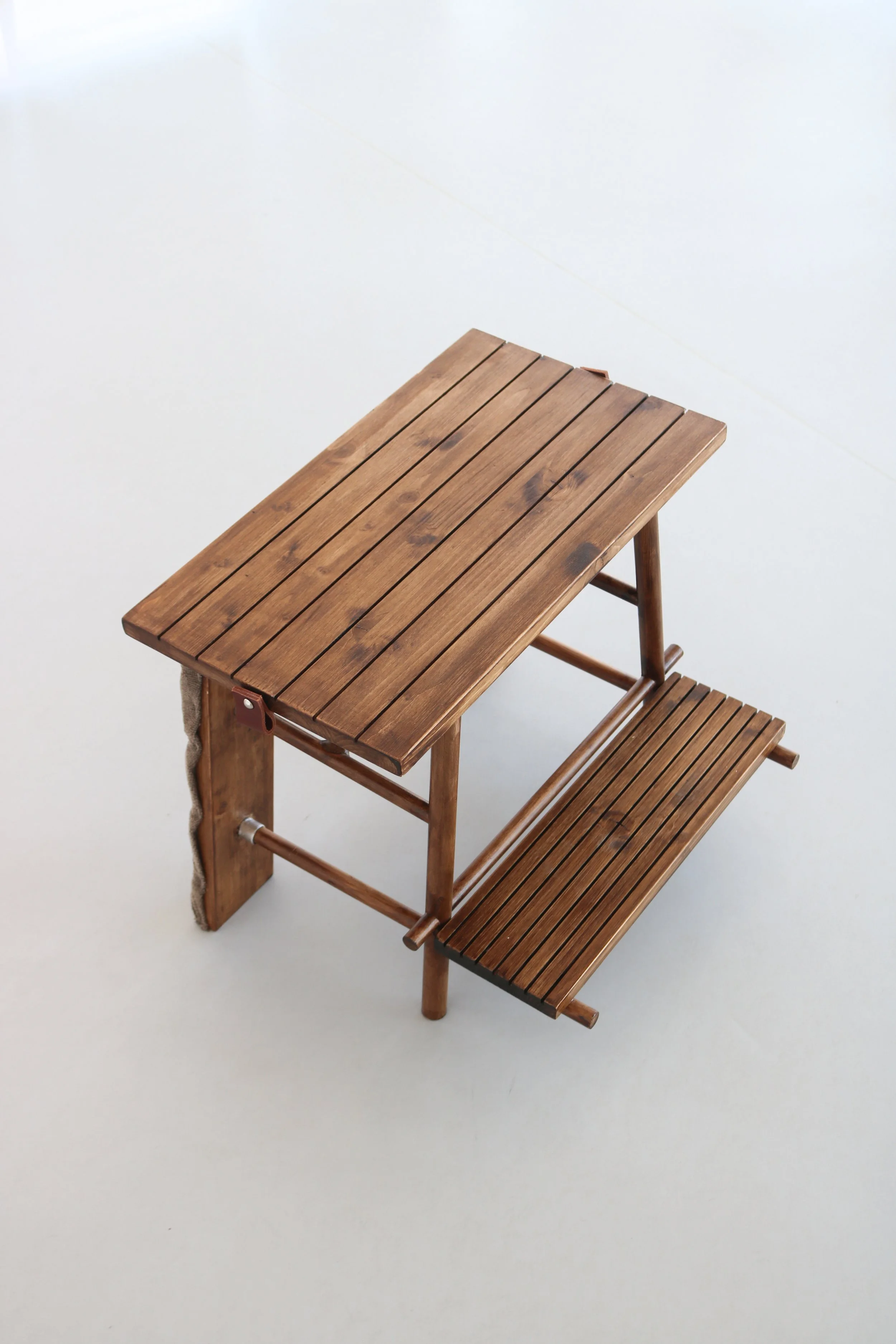 Table et banc en bois brun clair poussant à droite sur un fond blanc clair.