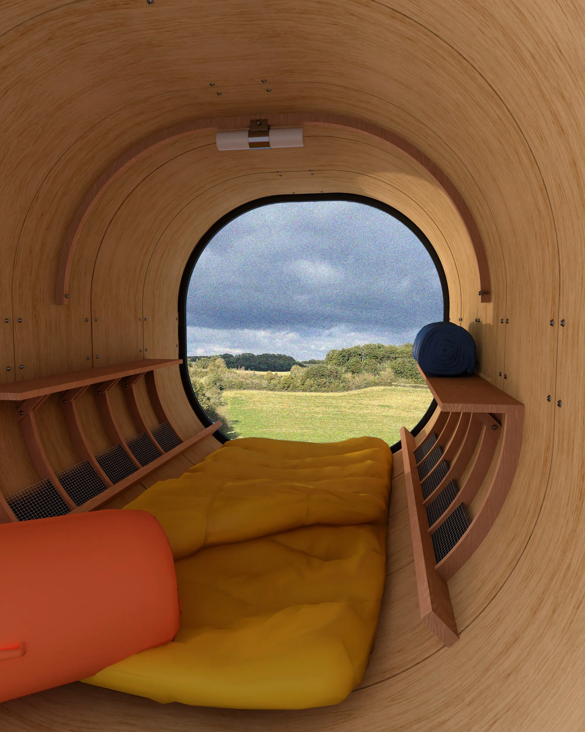 Intérieur d'une capsule en bois avec un grand cercle de fenêtre montrant un paysage rural avec des champs et des arbres, lit jaune avec coussin orange, étagères en bois et rouleau de tissu ou de vêtement à côté de la fenêtre.