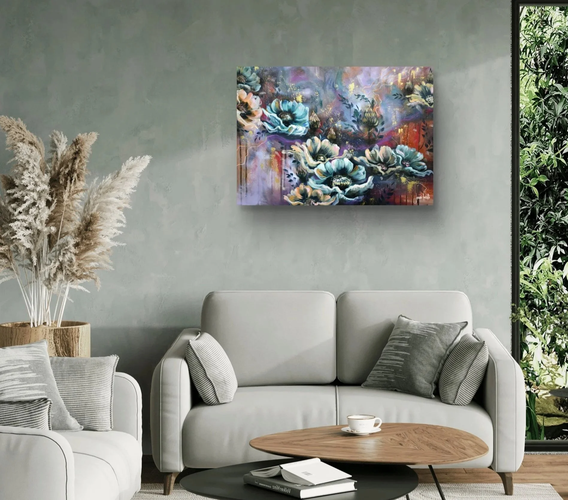 A modern living room with a gray wall, a white sofa with gray striped pillows, a wooden coffee table with a white cup and books, a large colorful floral painting on the wall, pampas grass in a pot on the left, and a large plant on the right.