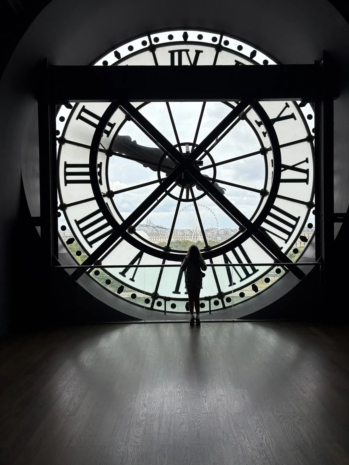 Image of solitary figure standing in the shadows by the clock window at the Musee d'Orsay in Paris, France