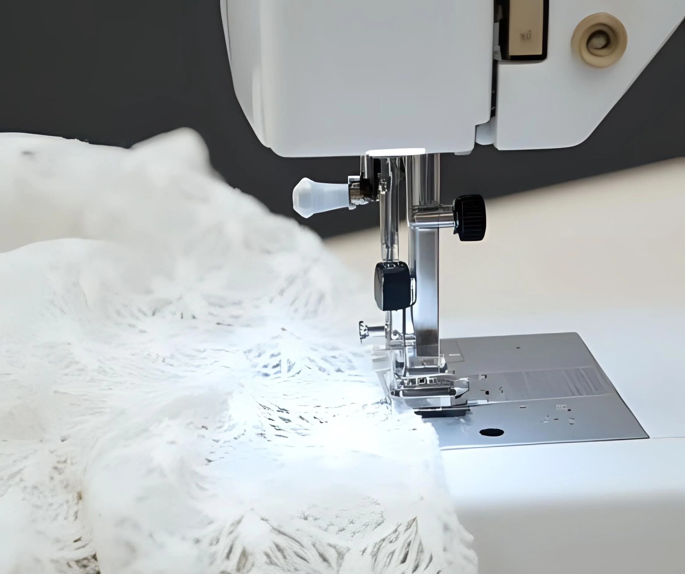 Close-up of a sewing machine stitching white fabric with a floral pattern.