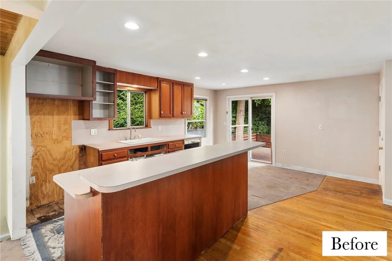 Empty kitchen with wooden cabinets, a window, and a sliding glass door leading to a deck, suggesting a renovation or remodeling in progress.