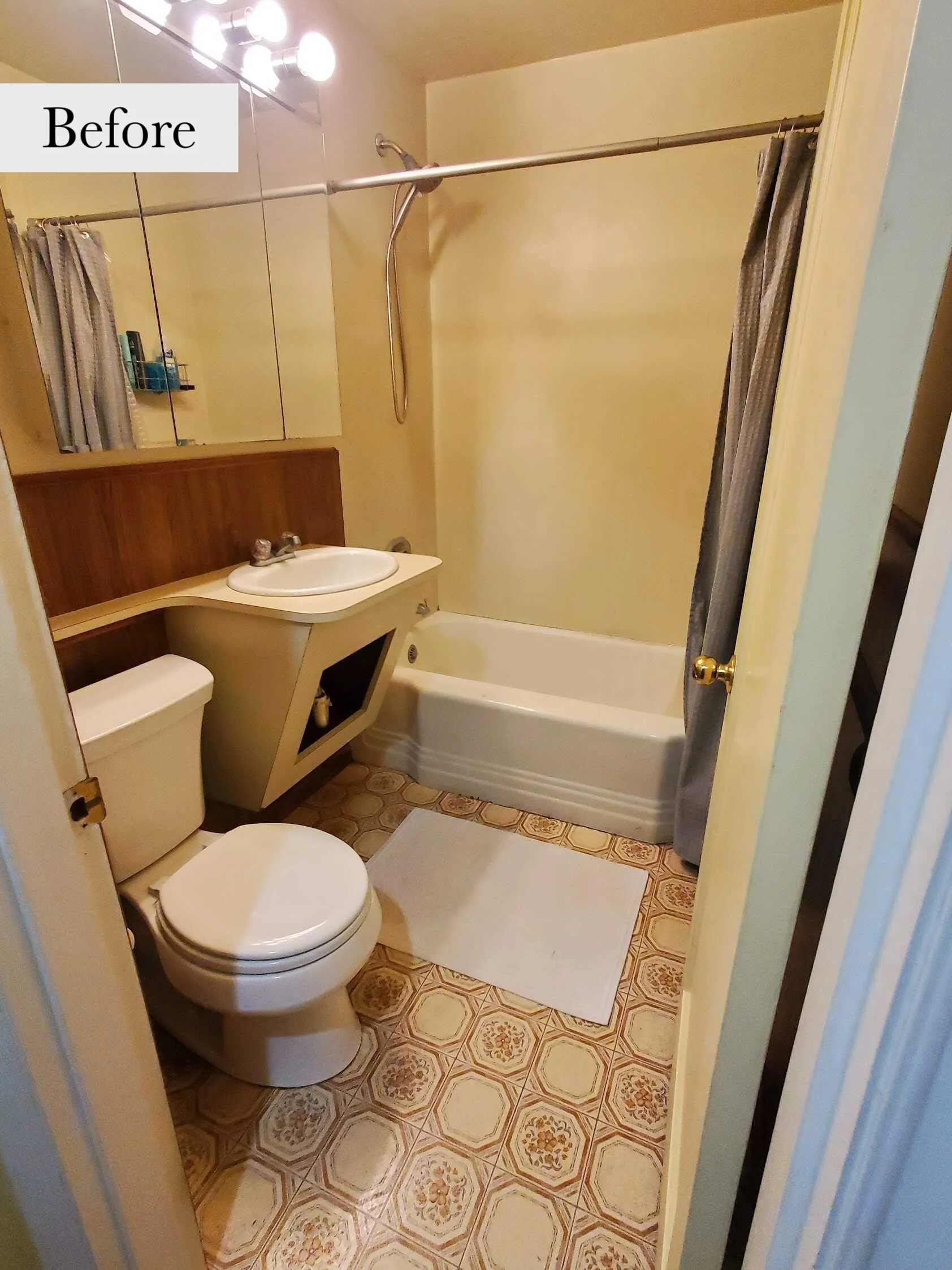 Bathroom with beige walls, a white toilet, a sink with a wooden cabinet, a bathtub with a gray shower curtain, and vintage patterned linoleum flooring. "Before" written in the top left corner.