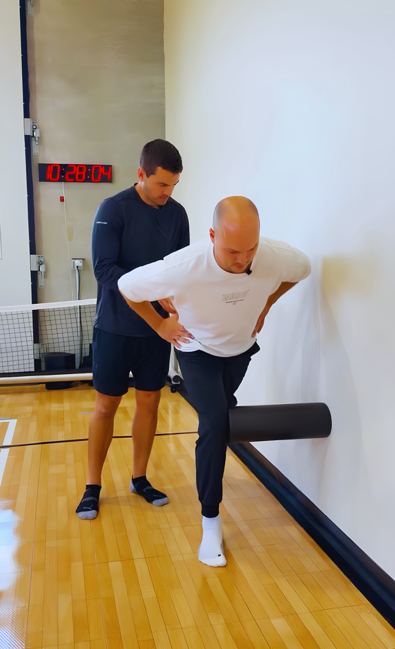 Dr. Grant Speer guides basketball creator Shane Hennen through a hip mobility exercise to improve movement and support basketball injury prevention.