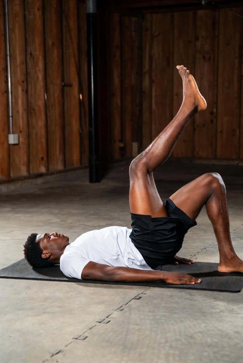 male basketball player performing single-leg glute bridge exercise for basketball injury prevention training