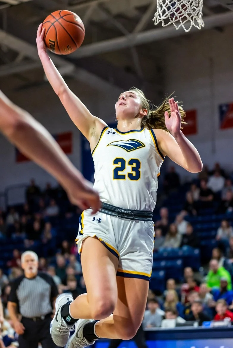 Girls basketball player performing layup during live game