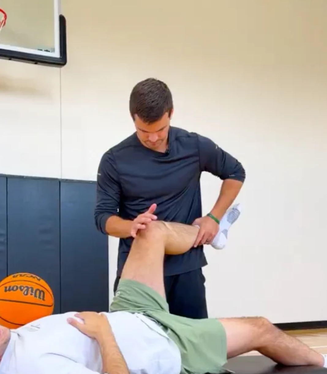 Dr. Grant Speer, DC, CSCS, evaluates basketball creator Shane Hennen's hip mobility and range of motion during a one-on-one movement assessment.
