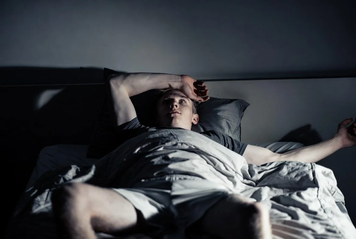 Athlete lying awake struggling to sleep after taking a stimulant pre-workout too late in the day.
