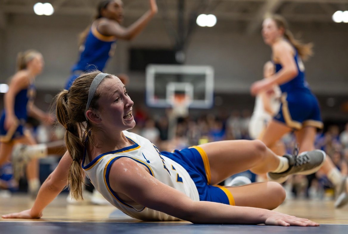 Youth female basketball player falling to the floor during a game after contact