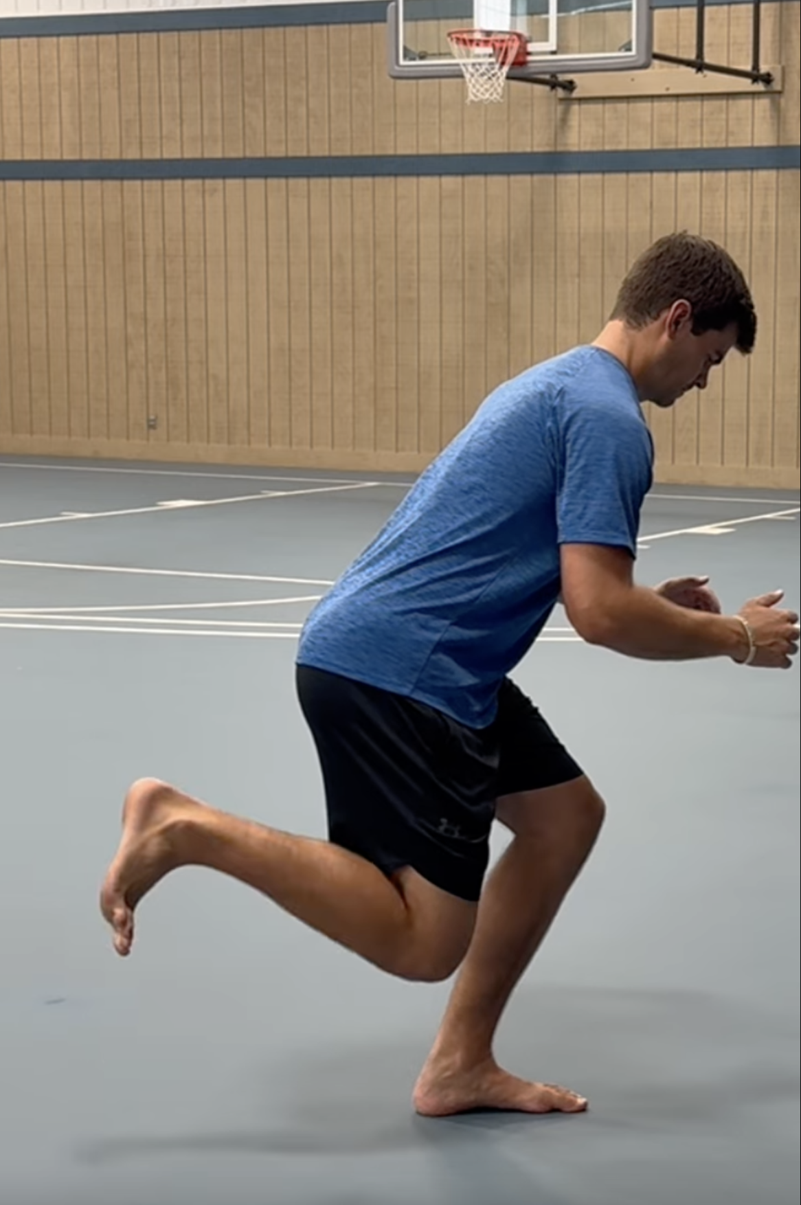 Basketball player performing a single-leg balance drill on a basketball court for injury prevention and durability training.
