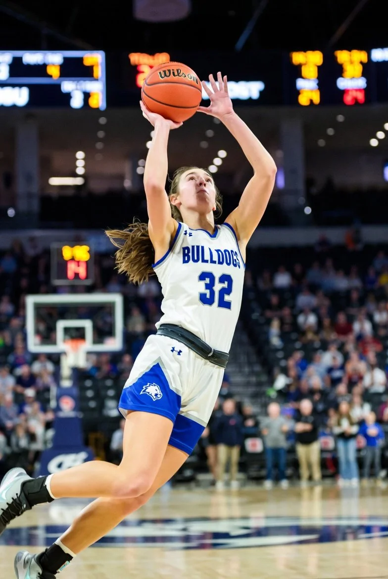Girls basketball player performing layup during game