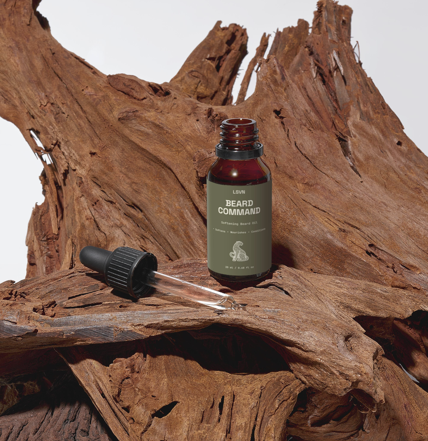 A small brown bottle labeled 'Beard Command' with a dropper cap, placed on a textured piece of wood
