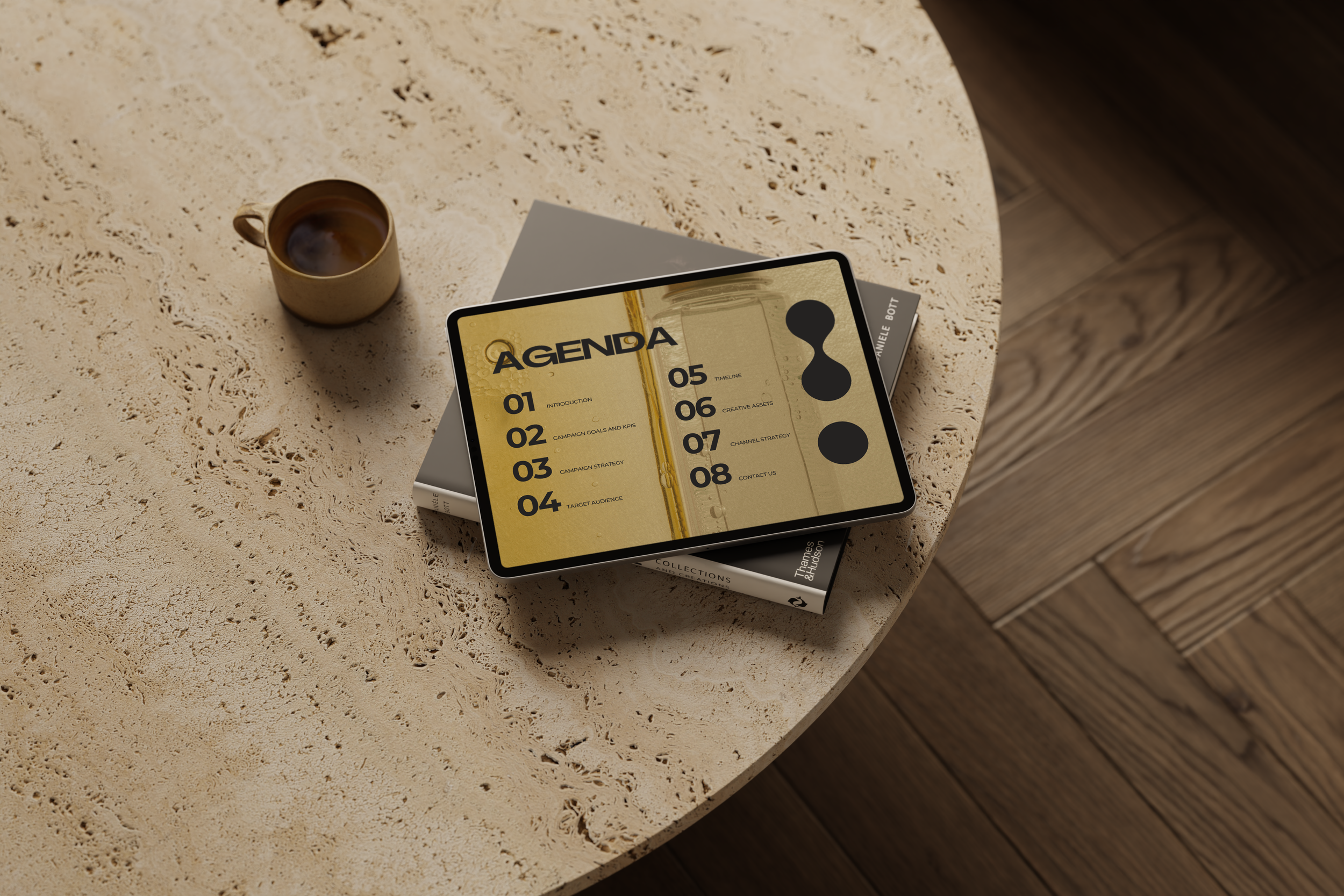 A tablet displaying an agenda with numbered items, a laptop underneath, a coffee mug, on a textured round table with wooden flooring.