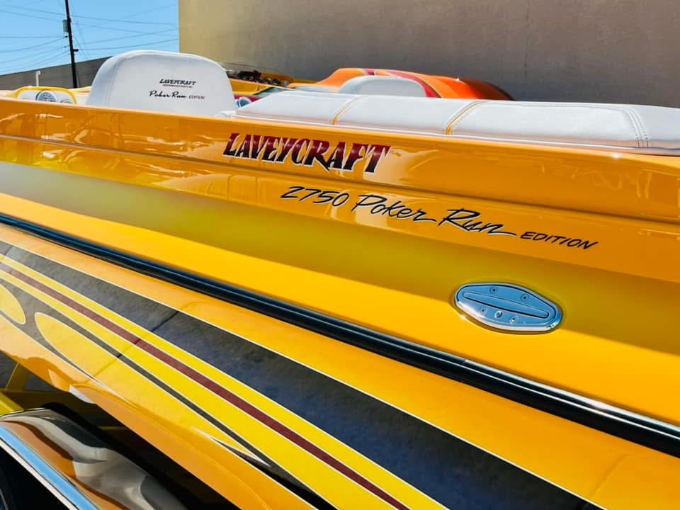 Yellow speedboat with 'LALYCRAFT 2750 Power Run EDITION' written on the side, parked outdoors with other boats visible in the background.