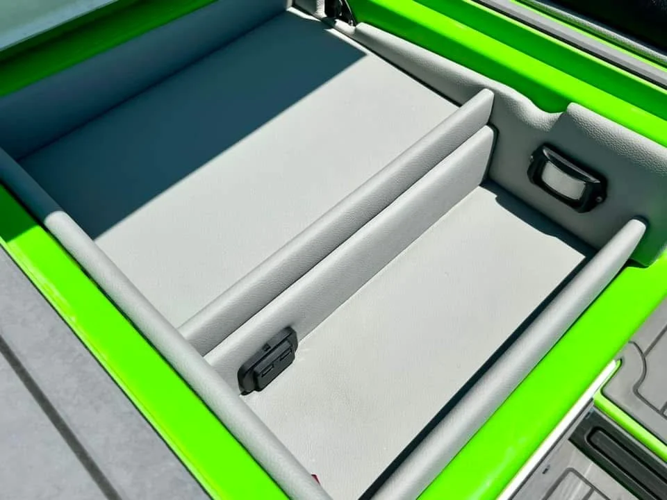 The interior of a bright green vehicle showing the open cargo bed with a light gray lining and a divider in the middle.