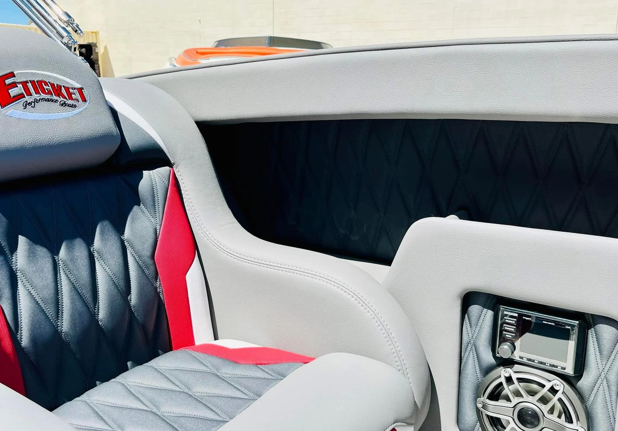 Close-up view of a boat interior featuring a cushioned seat with black, red, and gray upholstery and a stereo system.