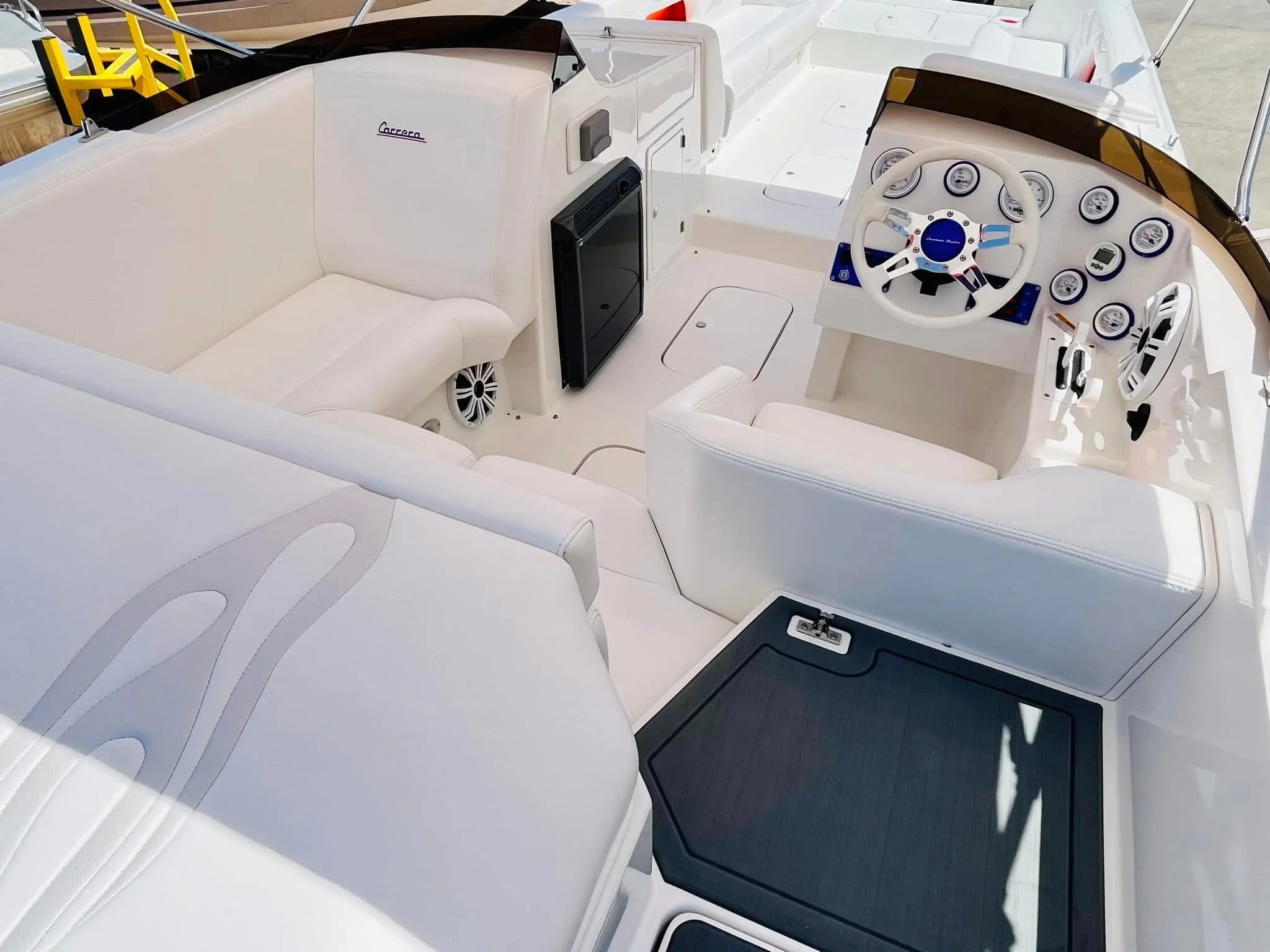 Interior of a luxury yacht with white leather seating, a steering wheel, and various gauges on the dashboard.