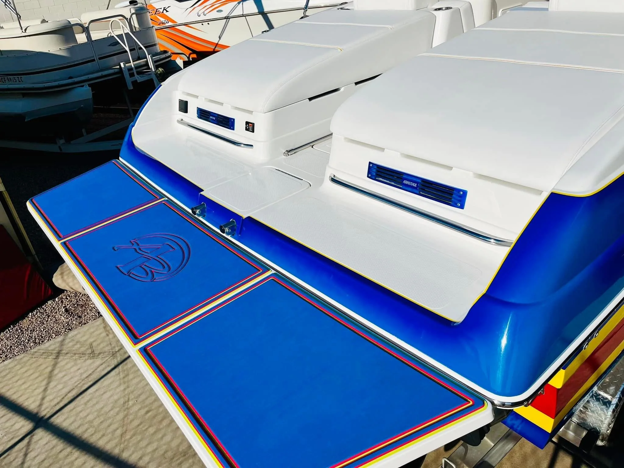 View of a boat's rear with colorful panels and two white fish finders or radar units installed on a boat deck, with other boats visible in the background.