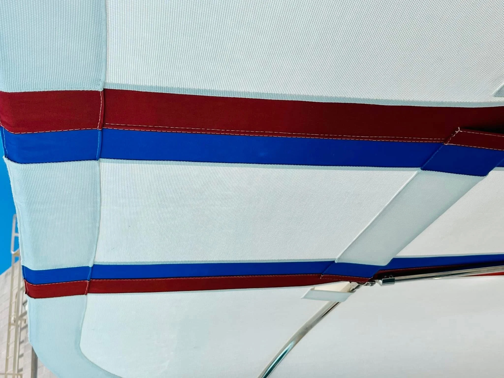 Close-up of a fabric awning with red and blue stripes on a white background.