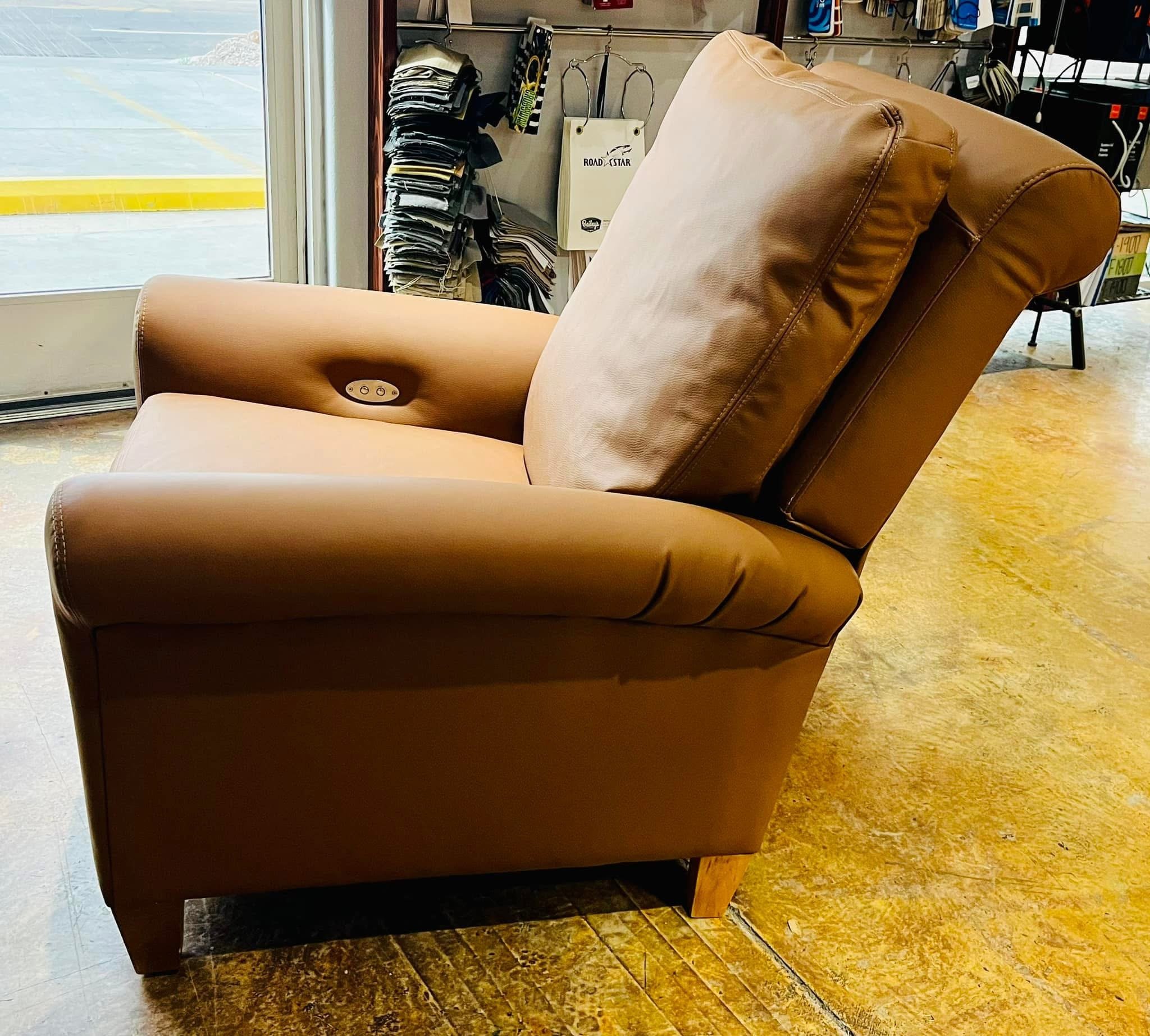 Brown leather reclining armchair in a store near a glass door.