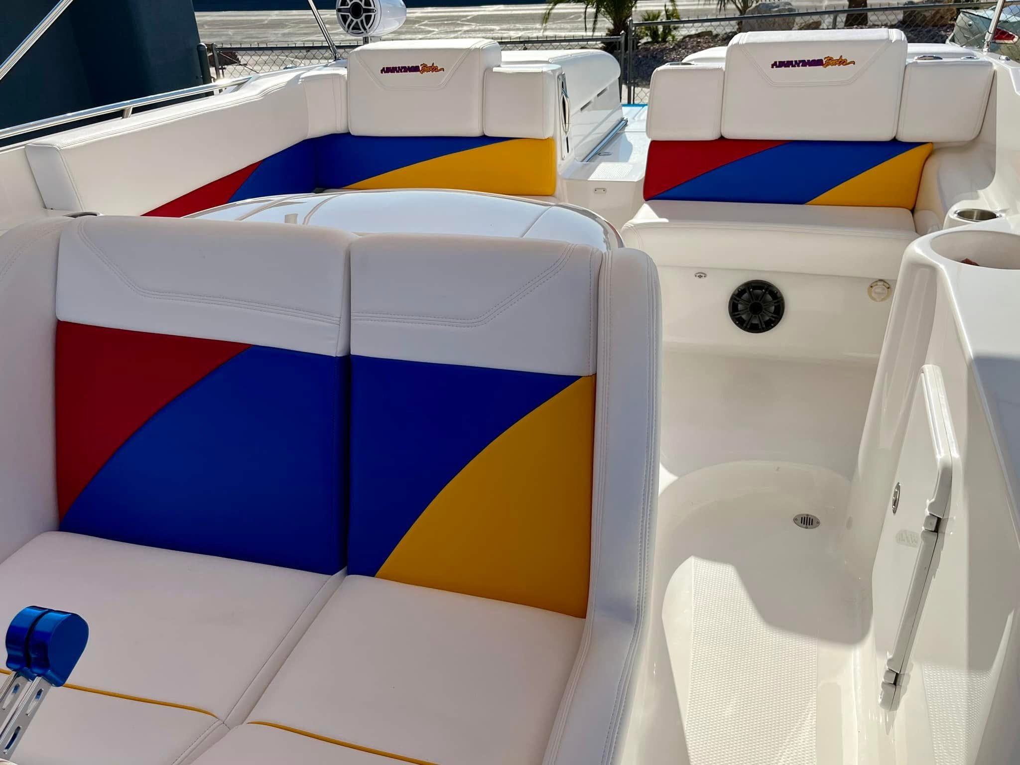 Colorful boat seats with red, blue, and yellow geometric patterns, featuring white borders and built-in speakers, within a boat's deck area.