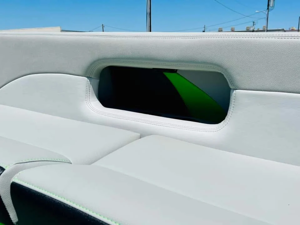 View through the back window of a car showing the interior ceiling and a small tinted window, with blue sky and power lines visible outside.