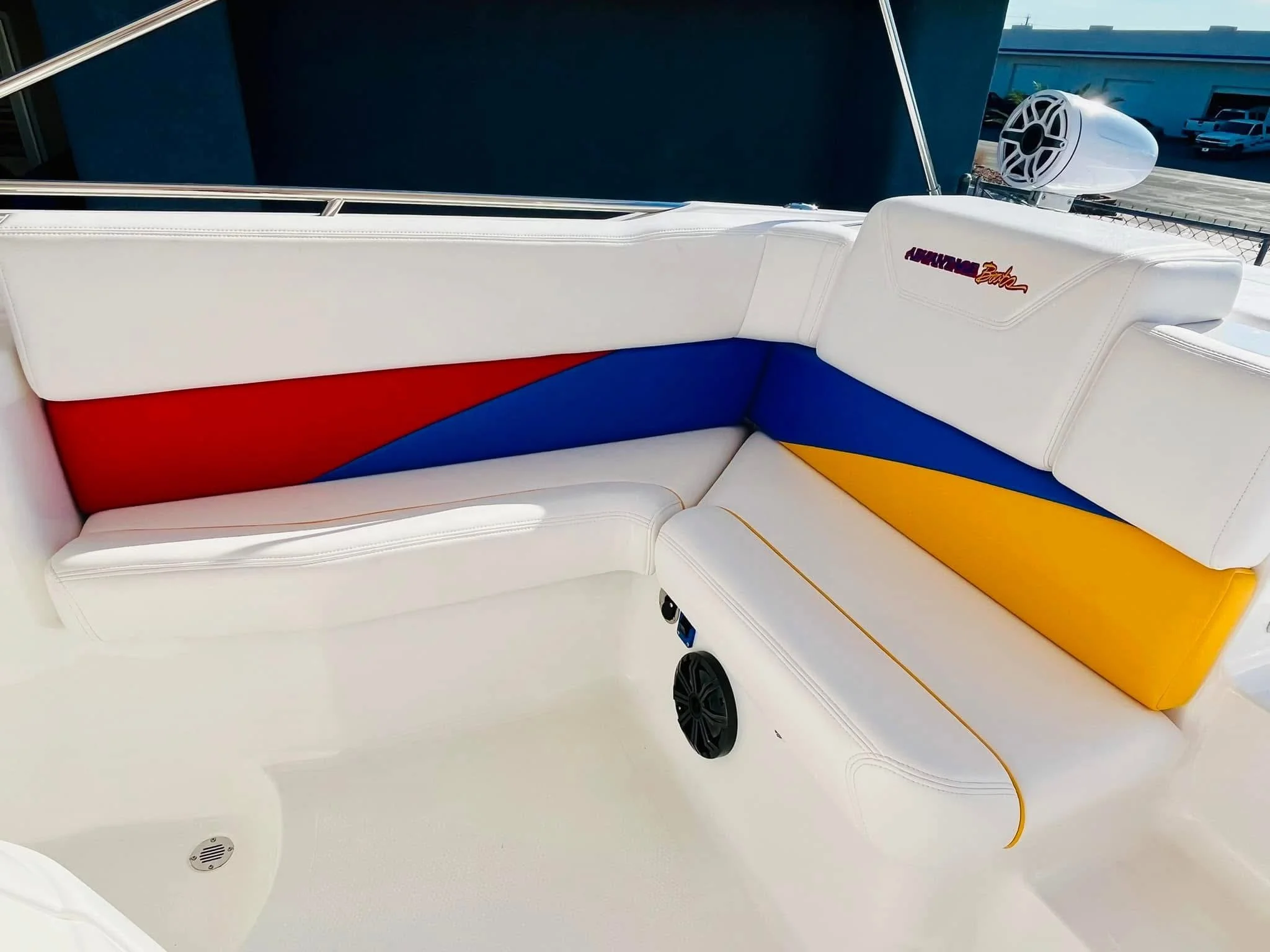 Colorful cushioned seats on a boat with a speaker and a logo on the headrest.
