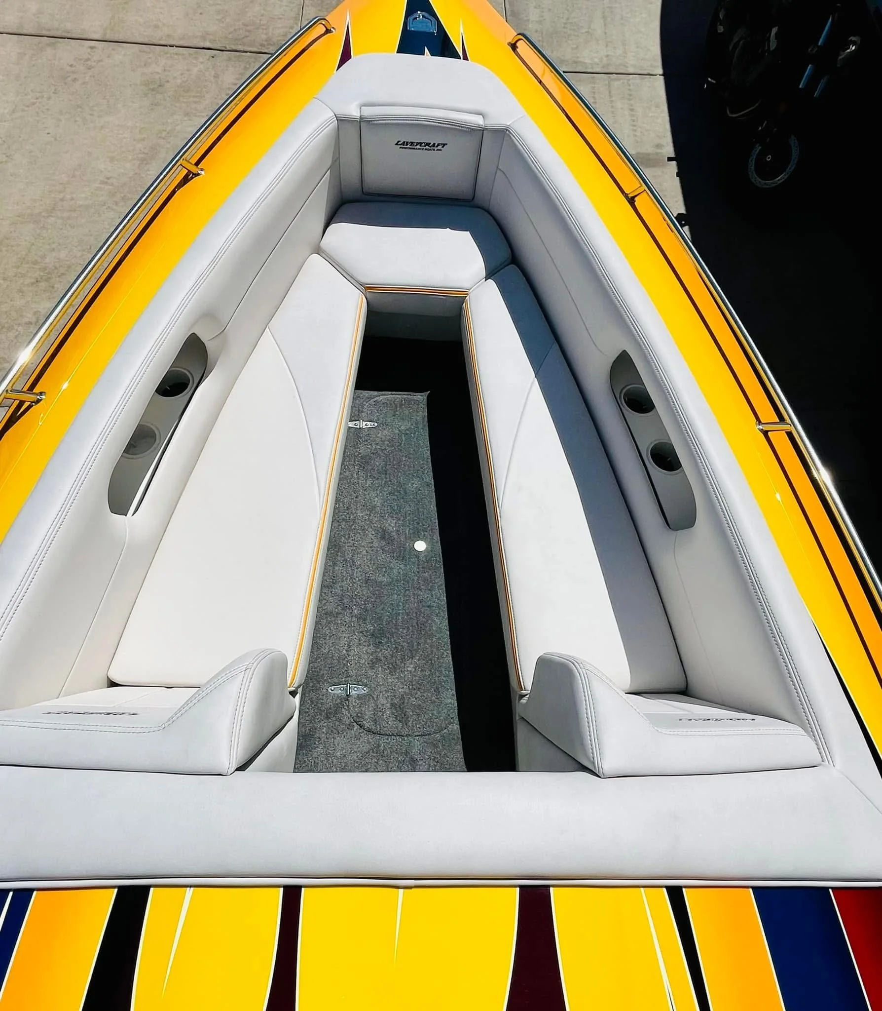 Overhead view of a yellow and colorful speedboat with white seating and speaker systems.