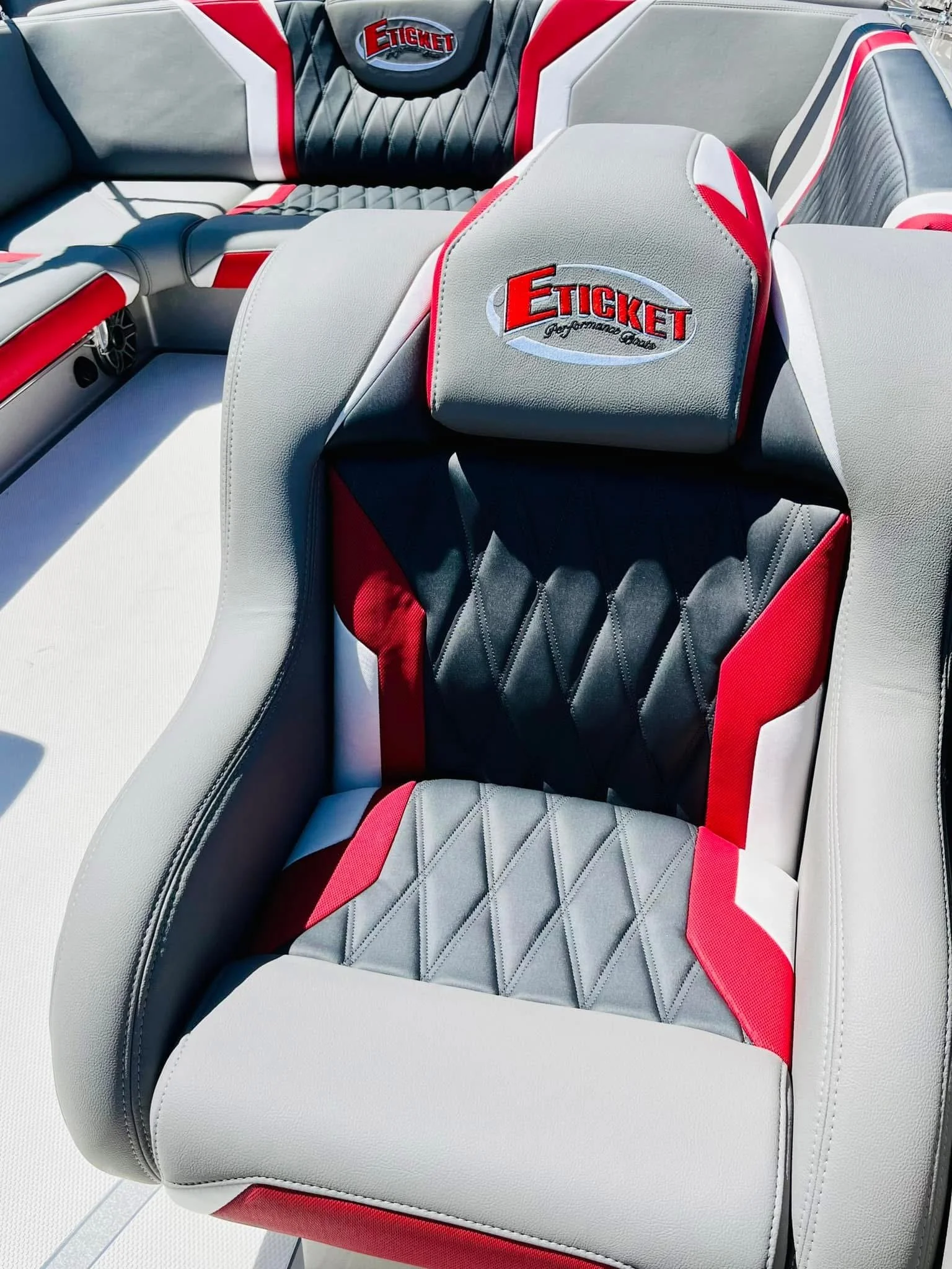 Close-up of boat seating with gray, white, black, and red upholstery, featuring embroidery of the Eticket Performance logo.