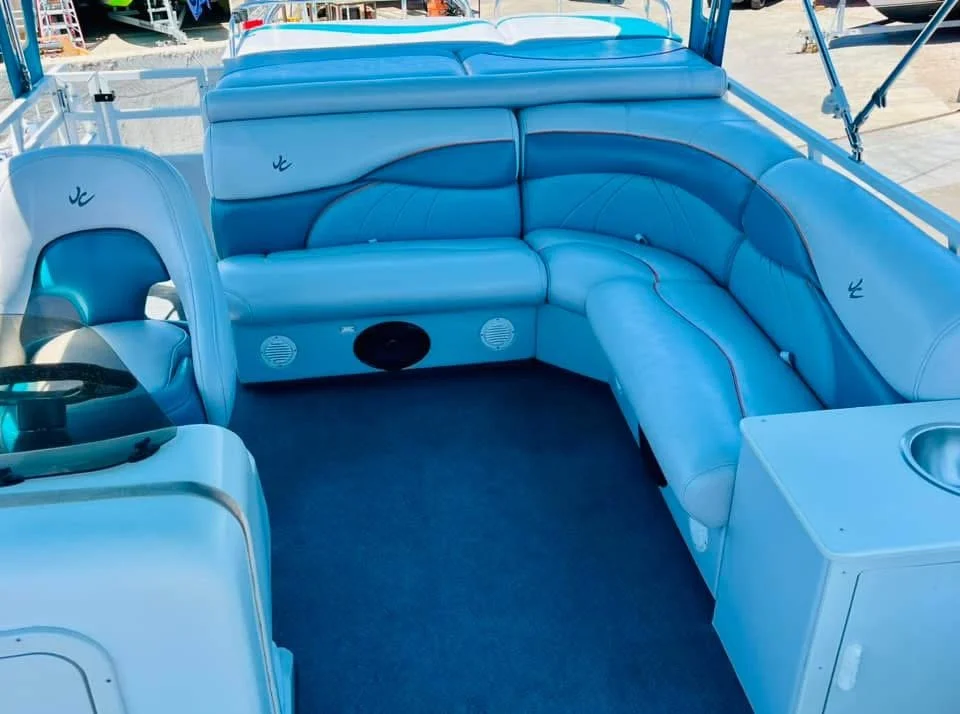 Blue pontoon boat interior with a cushioned seating area and steering wheel.