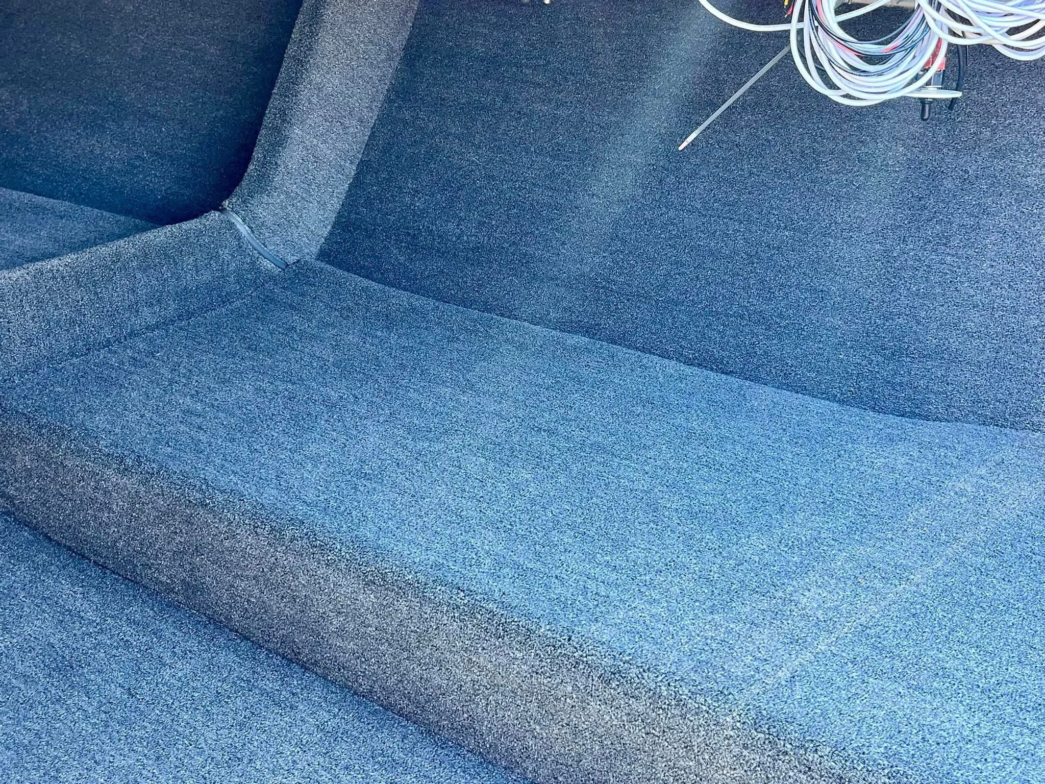 Close-up of a blue upholstered office chair with a bundle of cable wires resting on the seat.