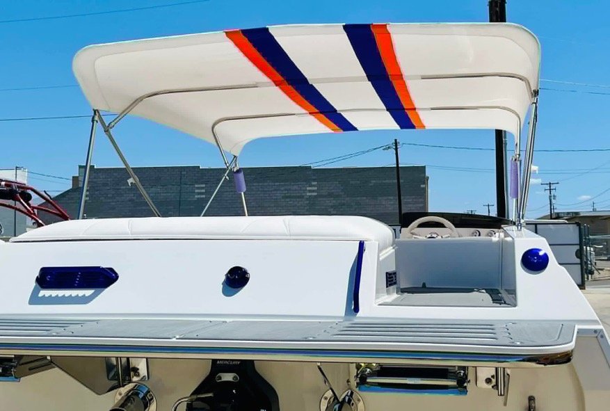 A white motorboat with a blue and red stripe canopy