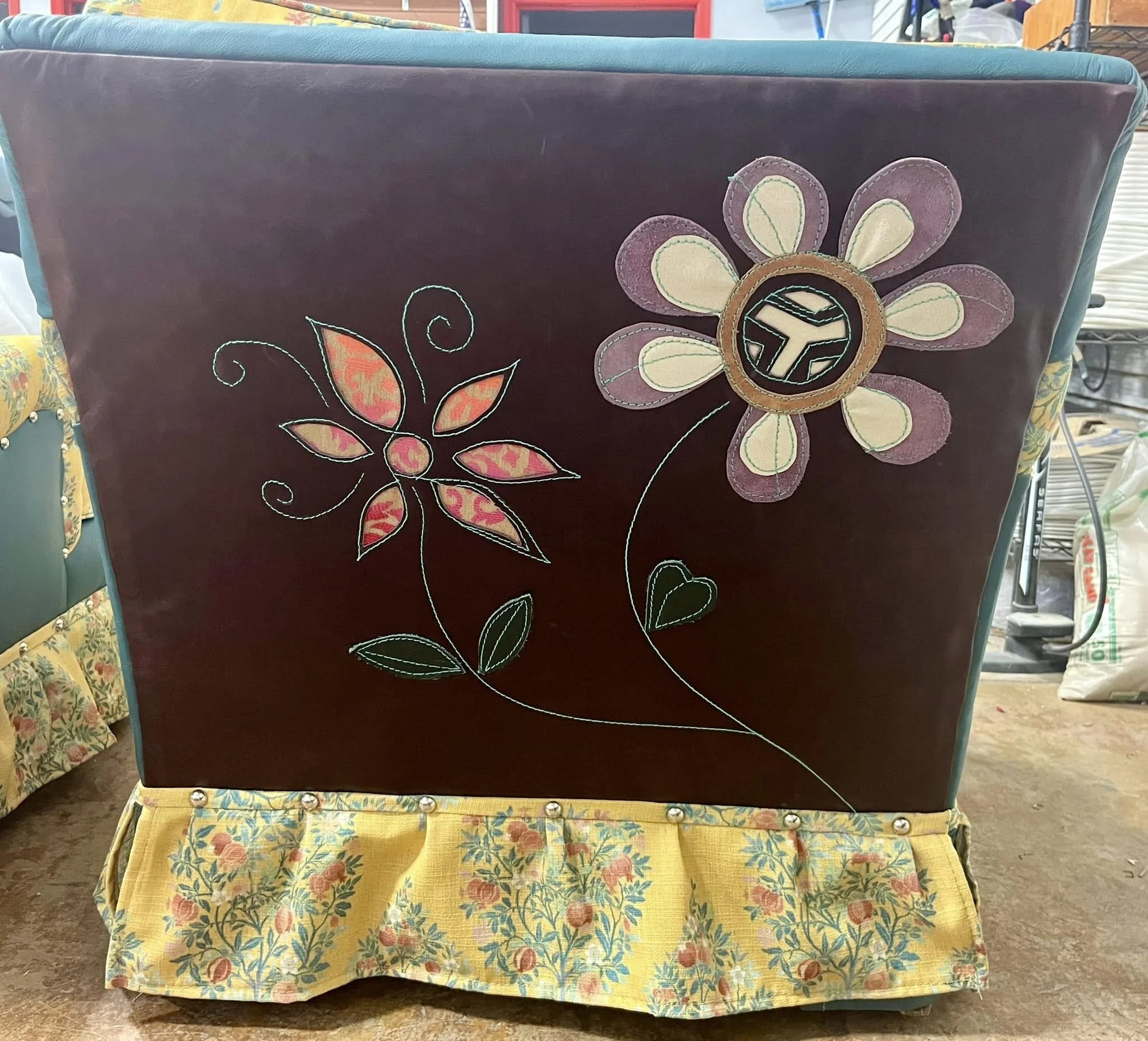 Decorative panel with embroidered floral design on a dark background, featuring two large flowers and a yellow fabric trim with a floral pattern at the bottom.