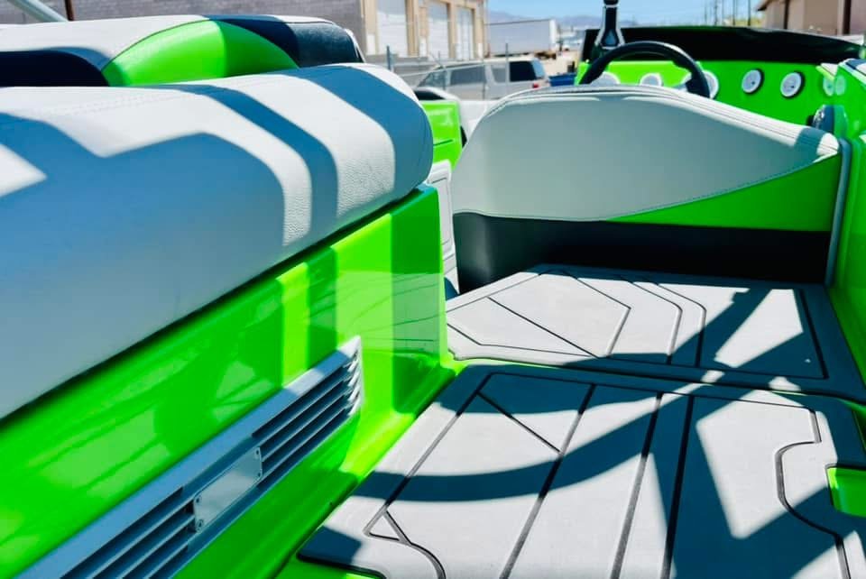 Close-up of a neon green and gray pontoon boat's seating area and deck with shadows cast by the boat's frame.