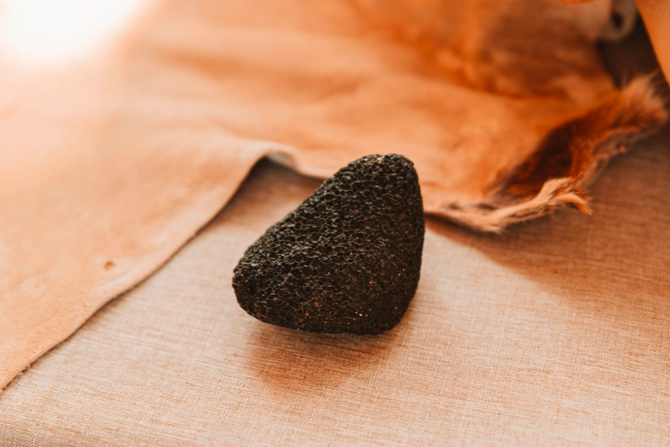 Volcanic pumice stone tool on tanned hide and linen background for hide tanning