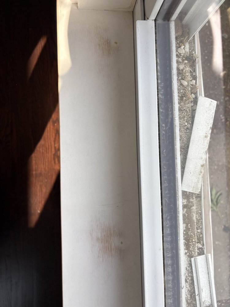 Window track full of construction dust and debris before cleaning