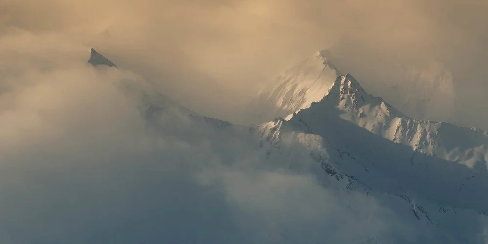 Snow-covered mountain peaks partially obscured by clouds and mist.